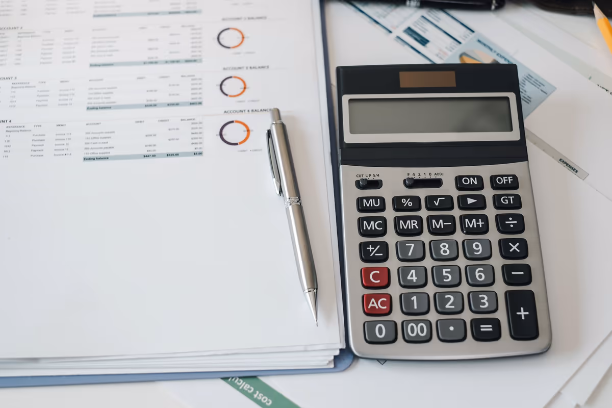 A calculator, a pen and financial charts