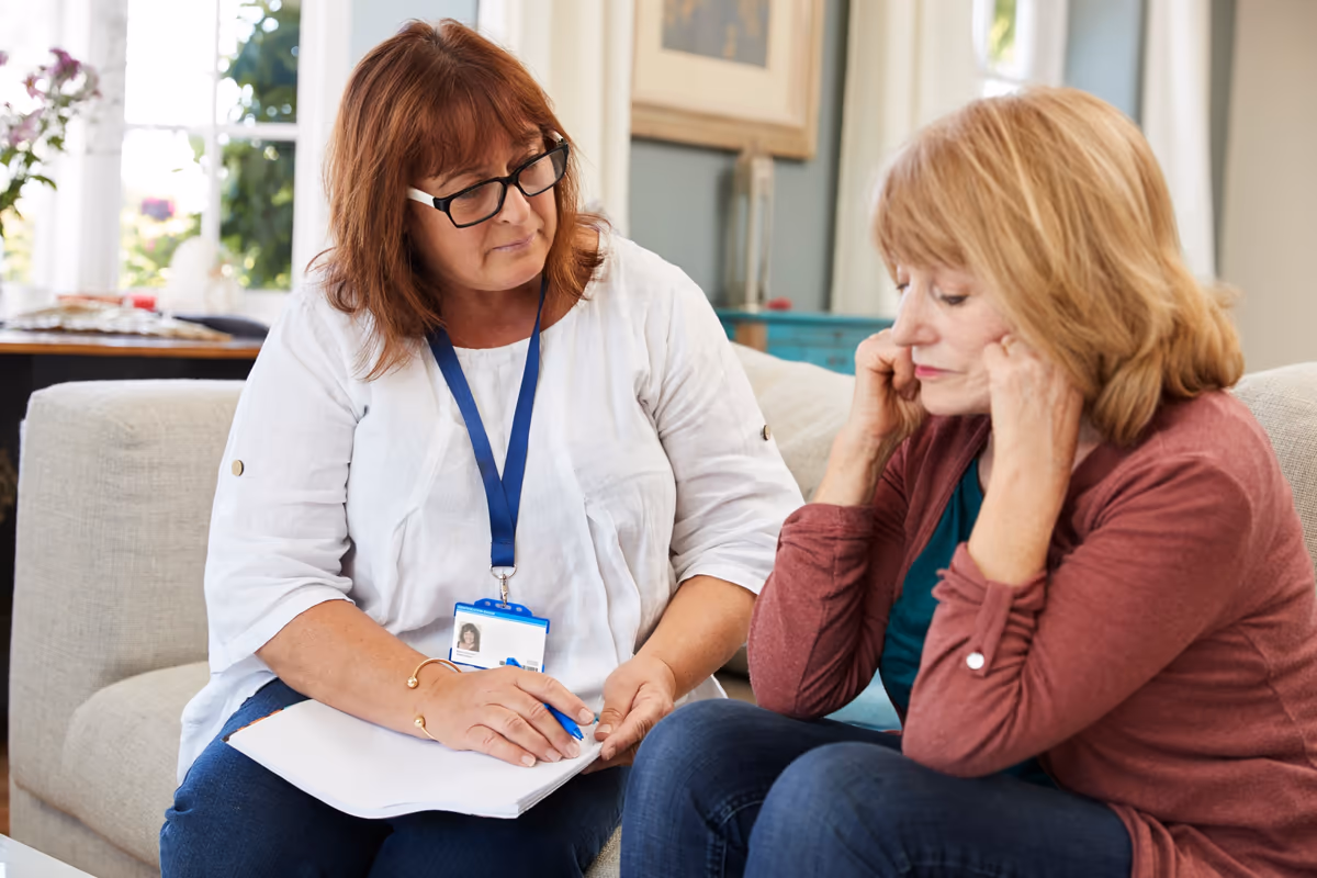 A caseworker with a clipboard talking with a worried mother