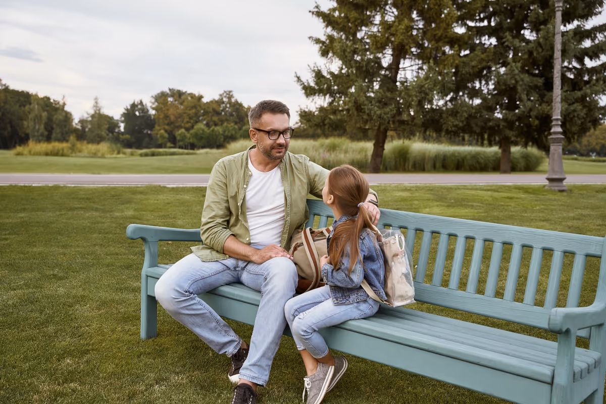 A father and his daughter sitting together on a park bench