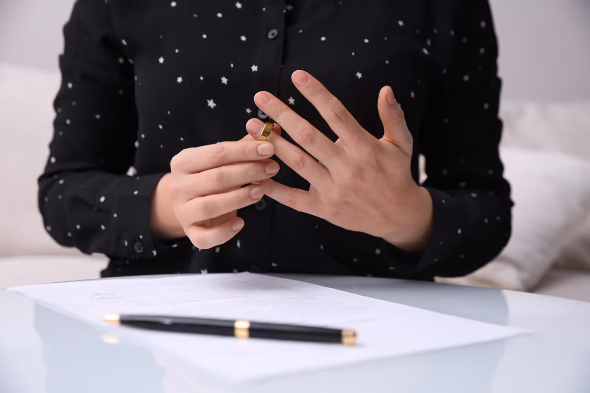 A woman taking off her wedding ring over a document