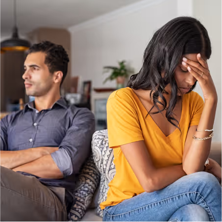 A couple sitting on a couch fighting